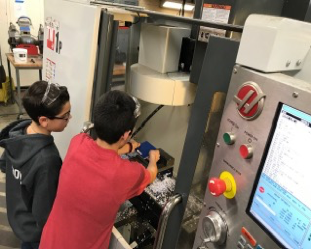 High School Students running a CNC Machine